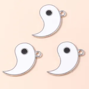 Detail of three white enamel Tai Chi fish charms with metal rings for DIY jewelry making