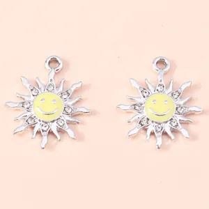 Macro detail of silver sun flower pendants with yellow enamel smile and sparkling rhinestones