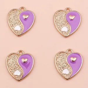 Close-up of heart-shaped Yin Yang charms in purple and gold for DIY jewelry making