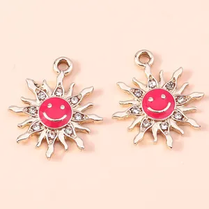 Close-up of alloy sun pendants with pink enamel smiley faces and small rhinestones