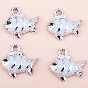 Close-up of enamel koi fish charms with blue and white stripes on a pink surface
