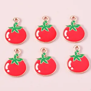 Detail of red enamel tomato pendants with gold-plated rims for DIY jewelry making