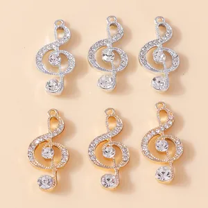 Detalle macro de colgantes de clave de sol en oro y plata con cristales para joyería