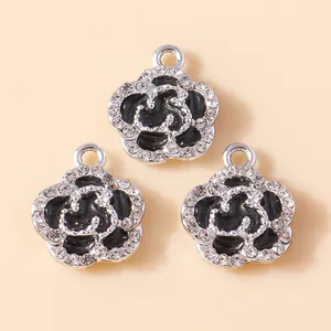 Macro detail of enamel camellia flower charms with silver frame and sparkling crystals