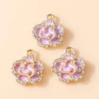 Macro detail of three purple enamel flower pendants with gold plating and white crystals