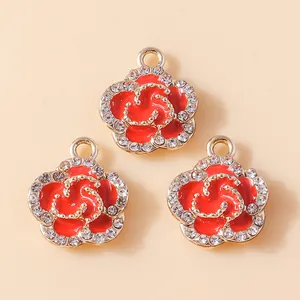 Detailed macro view of three red enamel camellia charms with gold base and clear rhinestones