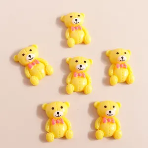 Détail de petits ours en résine jaune avec nœuds roses pour décoration de coque DIY