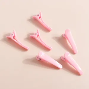 Primo piano di mollette per capelli in plastica rosa su sfondo beige minimale