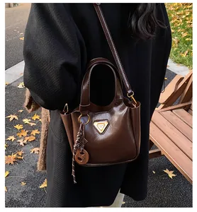 Close-up of dark brown leather bucket bag with metallic logo and woven charm detail