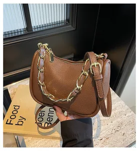 Détail d'un sac demi-lune marron en cuir grainé avec une chaîne dorée épaisse