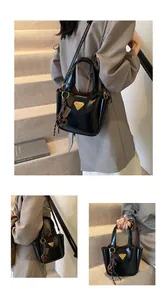 Detail shot of black bucket bag with gold triangle logo and tassel keychain charm