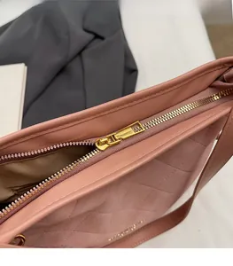 Détail d'un sac à bandoulière matelassé rose avec fermeture éclair dorée et texture fine
