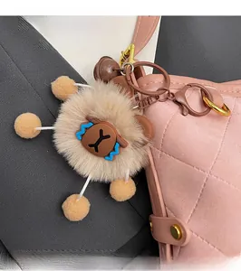 Détail d'un pendentif de sac en peluche marron avec pompons jaunes sur un sac à main rose