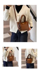 Detail of a brown glossy bucket bag featuring a gold triangle plaque and adjustable strap