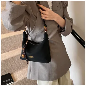 Detalle del bolso de hombro de nailon negro con herrajes dorados y colgante de campana