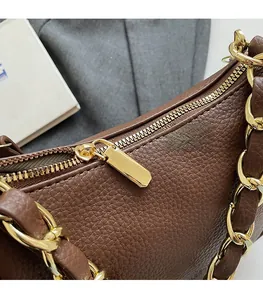 Détail du sac en cuir marron avec fermeture éclair dorée et bandoulière en chaîne