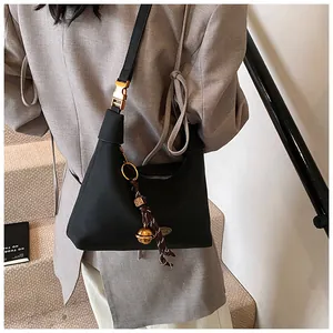 Detalle del bolso hobo negro con herrajes dorados y dije de campana tejida en modelo