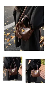Detail of dark brown leather tote featuring triangular gold metal plaque and charms