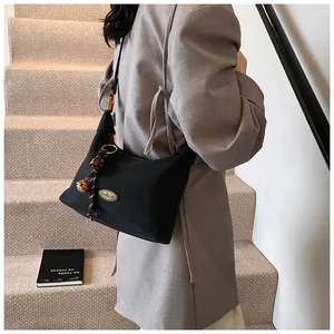 Detalle del bolso media luna de nailon negro con placa dorada y colgante de campana