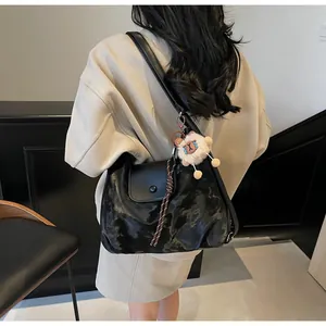 Schwarze Tragetasche mit Batik-Struktur und Plüsch-Anhänger an einem weiblichen Model