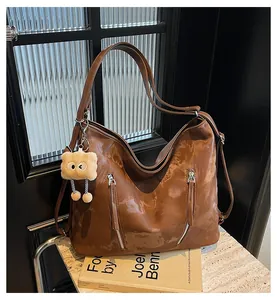 Close-up of brown vintage leather tote bag with dual zippers and a cute plush charm