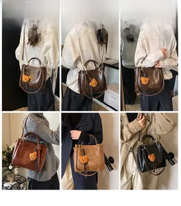 Detail view of large capacity vintage handbags in four colors with bear pendant charm