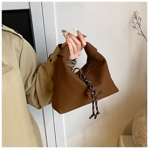 Detalle del bolso marrón oscuro con asa de nudo y cordón con bolas de metal dorado