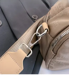 Gros plan sur la boucle métallique et la bandoulière de ce sac en nylon kaki