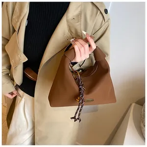 Detalle de bolso al hombro marrón vintage con herrajes dorados y adorno trenzado