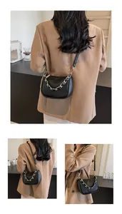 Détail du sac demi-lune en cuir grainé noir avec chaîne dorée et style urbain chic