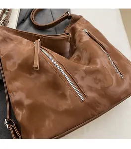 Detail of brown tote bag with vintage washed texture and diagonal metal zippers