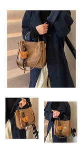Brown vintage leather bucket bag with plush bear charm and silk scarf detail
