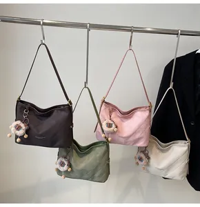 Détail de quatre sacs hobo matelassés en marron, vert, rose et blanc avec charms alpaga