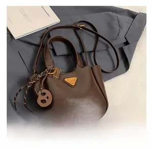 Close-up of brown leather bucket bag featuring a triangle metal logo and side charms