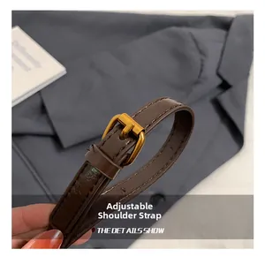 Detail of dark brown leather adjustable strap with gold-tone buckle and stitching