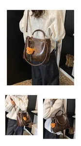 Detail of dark brown faux leather tote with plush bear charm and silk ribbon detail
