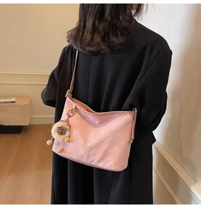 Gros plan du sac hobo matelassé rose avec pendentif en peluche et détails brodés