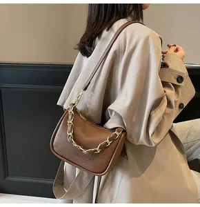 Détail du sac baguette en cuir marron à motif litchi avec chaîne et bandoulière