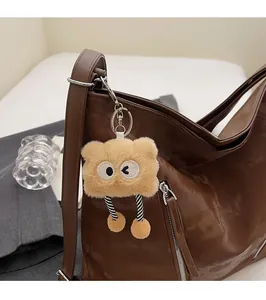 Detail of cute plush cartoon charm with long limbs on a brown shiny tote bag accessory