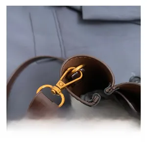 Macro detail of high-quality gold metal hook and stitching on brown leather bucket bag