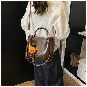 Detail of deep brown vintage tote bag with soft leather texture and bear charm