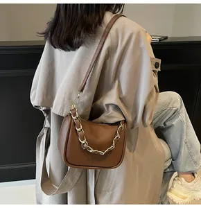 Détail du sac à main en cuir grainé marron foncé avec une élégante bandoulière chaîne dorée
