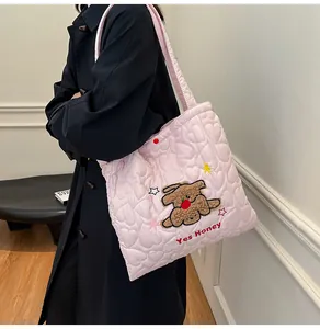 Dettaglio della borsa trapuntata rosa con cuciture a cuore e ricamo di orsetto