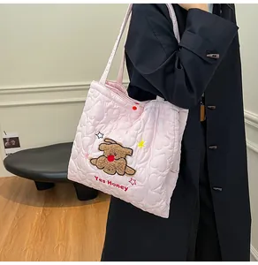 Dettaglio della borsa tote trapuntata rosa chiaro con motivi a cuore e ricamo cane