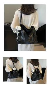 Detail view of a black glossy tote bag with dual zippers and cloud charm detail