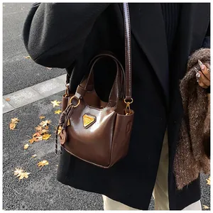 Detail of vintage brown patent leather bucket bag with gold hardware on black coat