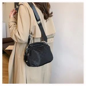 Détail du sac bandoulière en nylon noir avec lettrage gaufré et large sangle réglable