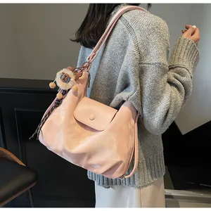 Detail der rosa Nylon-Einkaufstasche mit Plüschlöwen-Anhänger und karierter Schleife