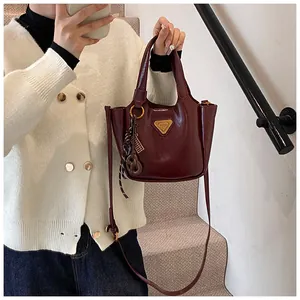 Detailed shot of the burgundy glossy bucket bag featuring a signature triangle metal logo
