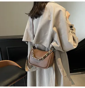 Détail du sac en cuir marron à motif litchi avec chaîne métallique dorée décorative